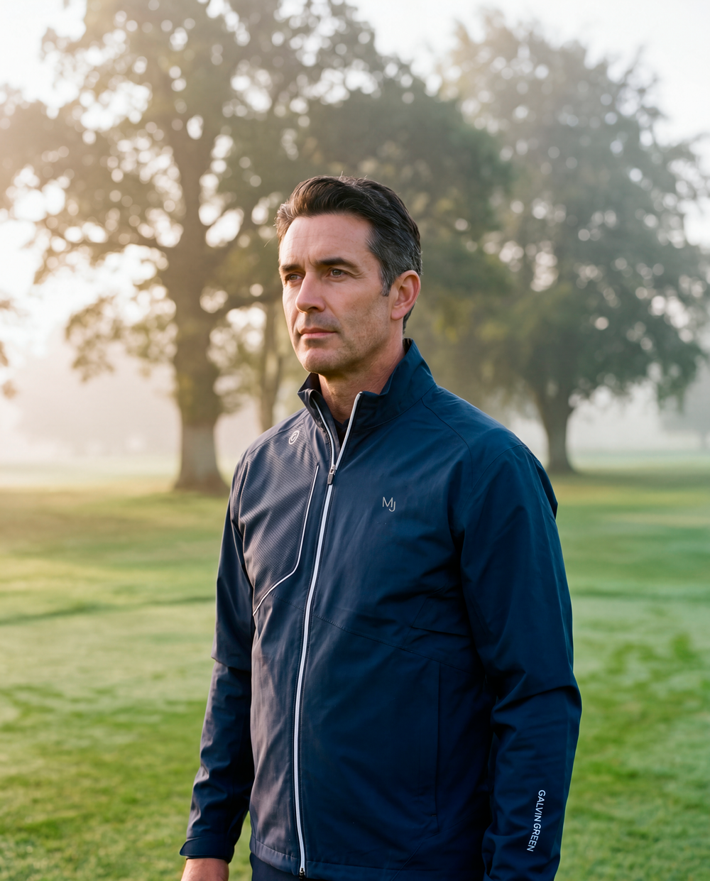 A golfer wearing a HLINC navy blue rain jacket with the Mount Juliet logo